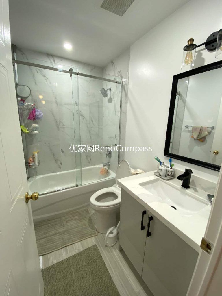 This image showcases a completed bathroom renovation in Mississauga, featuring a full-size bathtub with sliding glass shower enclosure, marble-look wall tiles, and a modern vanity with integrated storage. The layout is designed to maximize functionality within a compact footprint, combining moisture-resistant materials, clean finishes, and efficient lighting. Neutral tones and durable tile flooring enhance brightness while supporting easy maintenance for everyday use. This bathroom renovation reflects the practical design approach and workmanship delivered by a professional Toronto renovation company focused on long-term comfort and reliability.