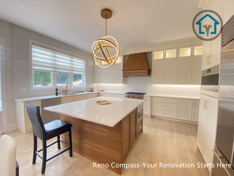 This image showcases a custom kitchen design within a Richmond Hill interior renovation, featuring a warm wood-finished island paired with white cabinetry and a clean, modern layout. A sculptural pendant light above the island creates a strong visual focal point, while integrated appliances and layered lighting enhance everyday functionality. Designed and completed by Reno Compass, this kitchen reflects a balanced approach to material contrast and practical design for homes in Richmond Hill.