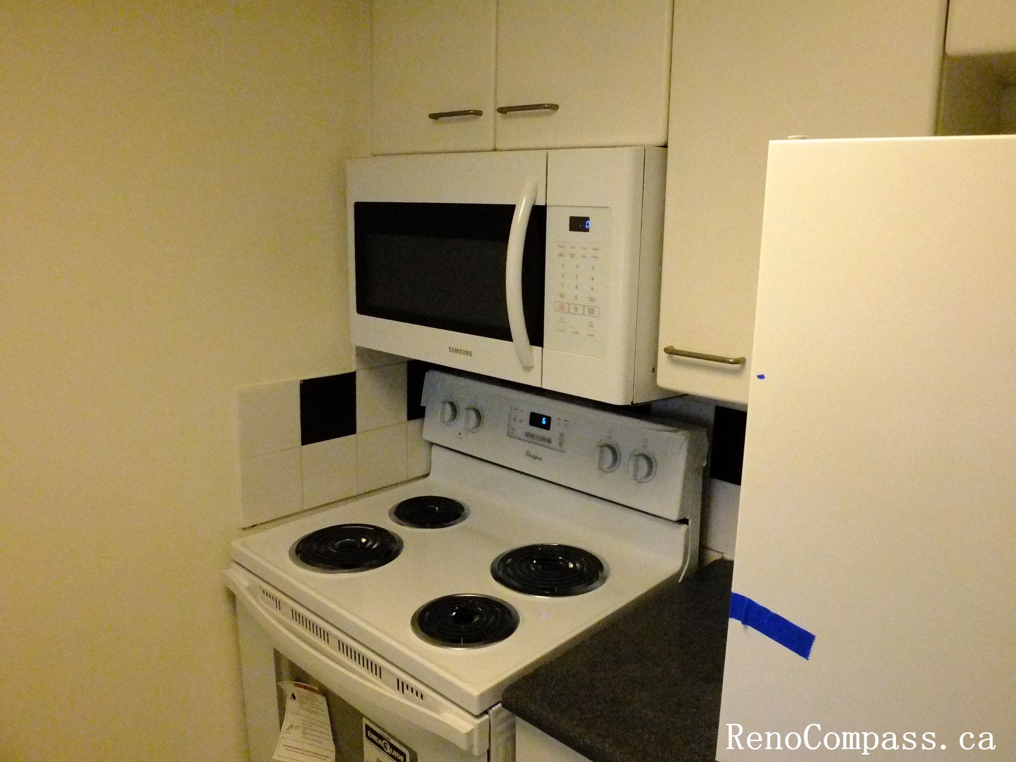 Toronto condo kitchen renovation featuring upgraded cabinetry, electric stove, and built-in microwave installation. The project improves kitchen functionality and creates a clean, modern cooking space within a compact condo layout.
