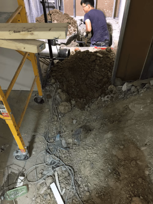 This image shows the early construction phase of a commercial retail store renovation, including floor excavation and underground plumbing preparation. The renovation team is performing structural groundwork to support new drainage, utility lines, and flooring installation for the upgraded retail space. Reno Compass Inc. ensures all foundational and infrastructure work is completed with precision to support a safe, durable, and high-quality commercial renovation.