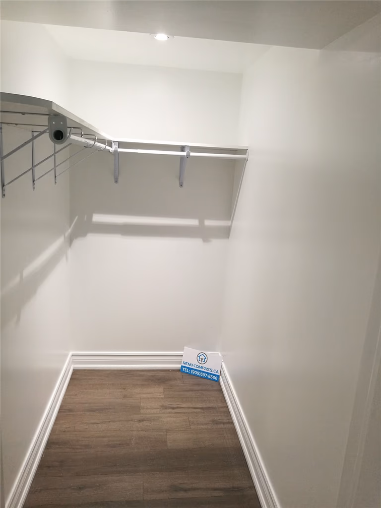 Custom walk-in closet from a Pickering interior renovation project, featuring built-in shelving, hanging rails, new flooring, and clean white finishes. This functional storage upgrade improves organization and everyday use, completed by a professional Toronto renovation company.