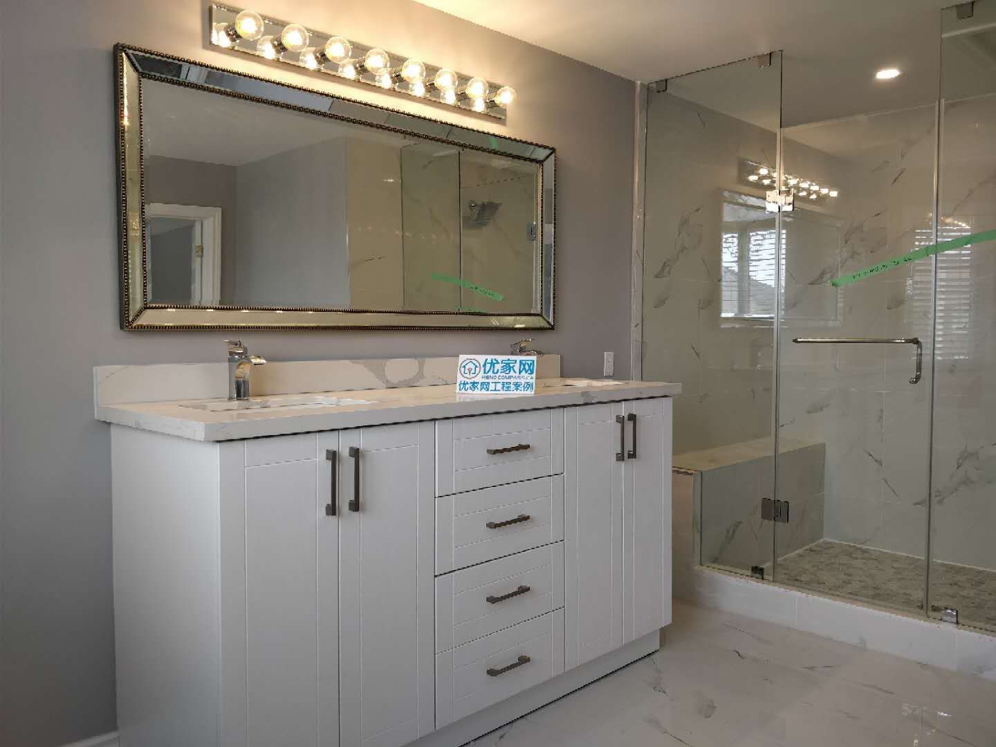 This modern bathroom renovation in Ajax features a double sink vanity with quartz countertop, a large framed mirror with upgraded lighting, and a glass-enclosed walk-in shower. The clean layout and premium materials create a spa-like atmosphere while improving daily functionality. As part of a full house renovation, this bathroom design combines elegance, durability, and modern comfort.