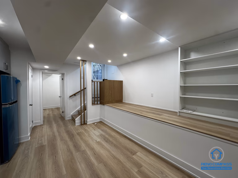 This basement living area features a raised platform and built-in shelving as part of a Toronto legal 3-unit conversion. The design maximizes usable space, improves layout functionality, and enhances comfort for rental living.