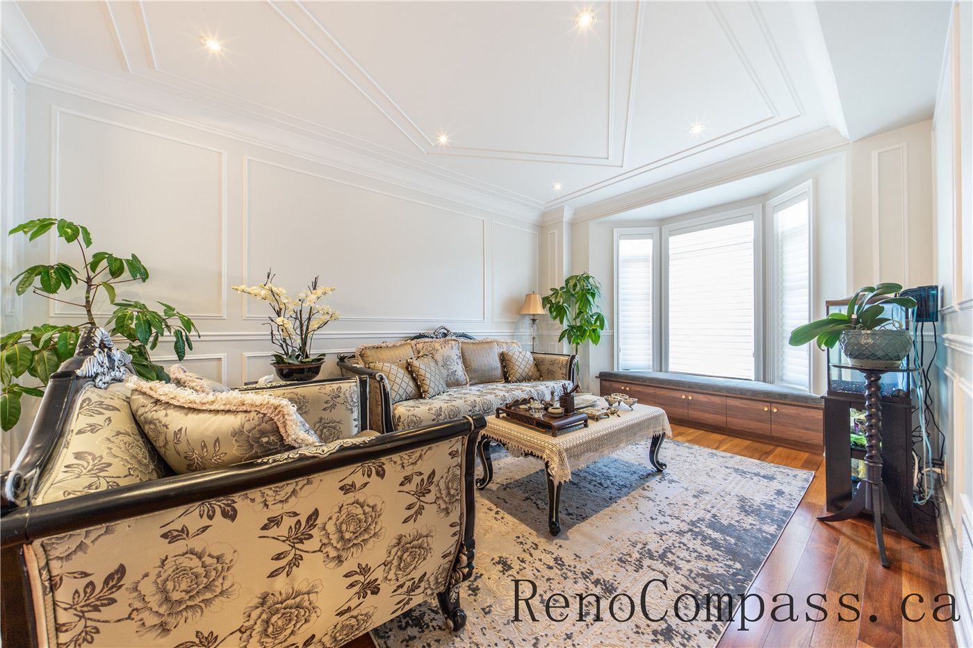 This Richmond Hill entire house interior renovation showcases a refined living room with custom wall paneling, elegant ceiling details, and warm hardwood flooring. Large bay windows bring in abundant natural light, enhancing the open and welcoming atmosphere. Classic furniture styling combined with modern finishes creates a timeless and luxurious space, professionally completed by a trusted Toronto renovation company to elevate comfort, functionality, and visual appeal.