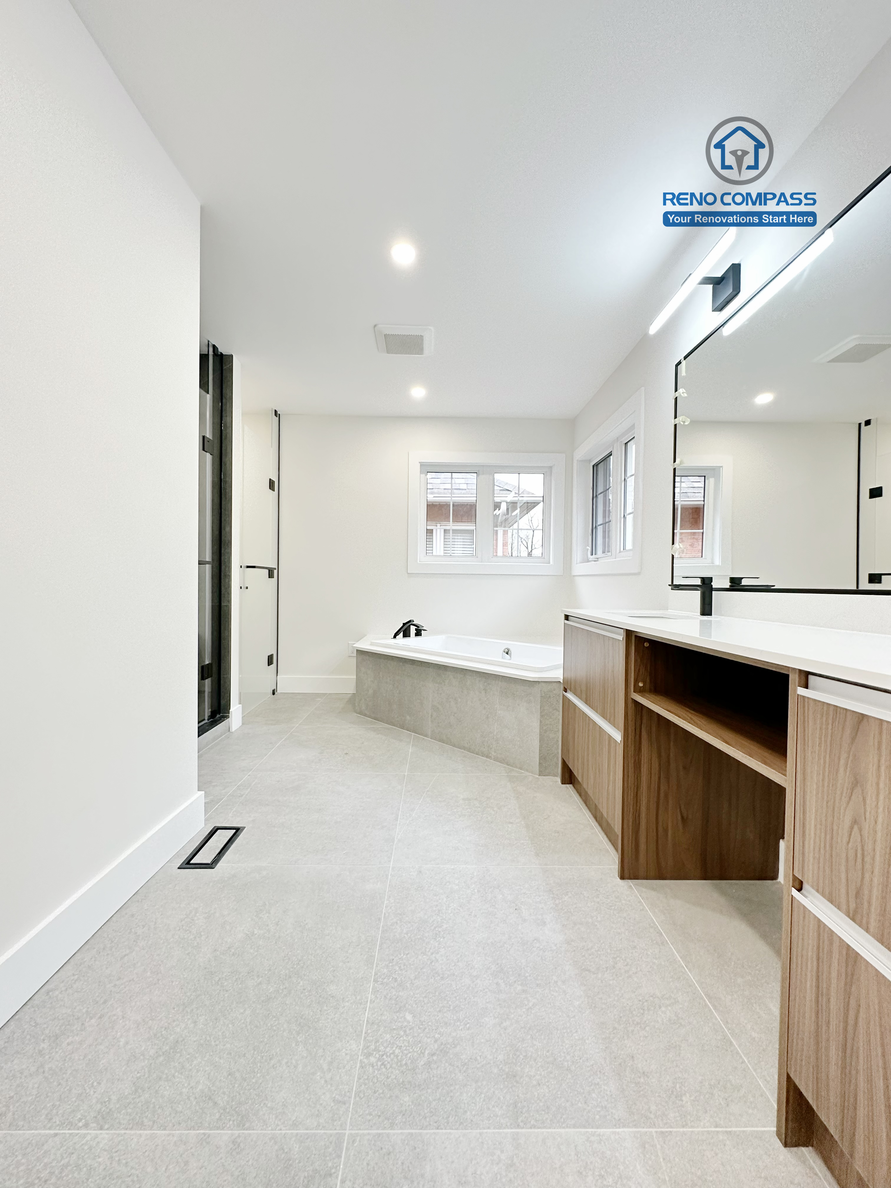 Full bathroom renovation in Richmond Hill showcasing a spacious and open layout with a modern soaking tub, large-format floor tiles, custom vanity cabinetry, and clean architectural lines for a bright and relaxing bathroom space.