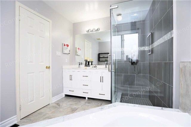 A beautifully remodeled bathroom featuring a frameless glass shower, sleek white vanity, and neutral tile design. Perfect inspiration for a modern home renovation in the Greater Toronto Area.