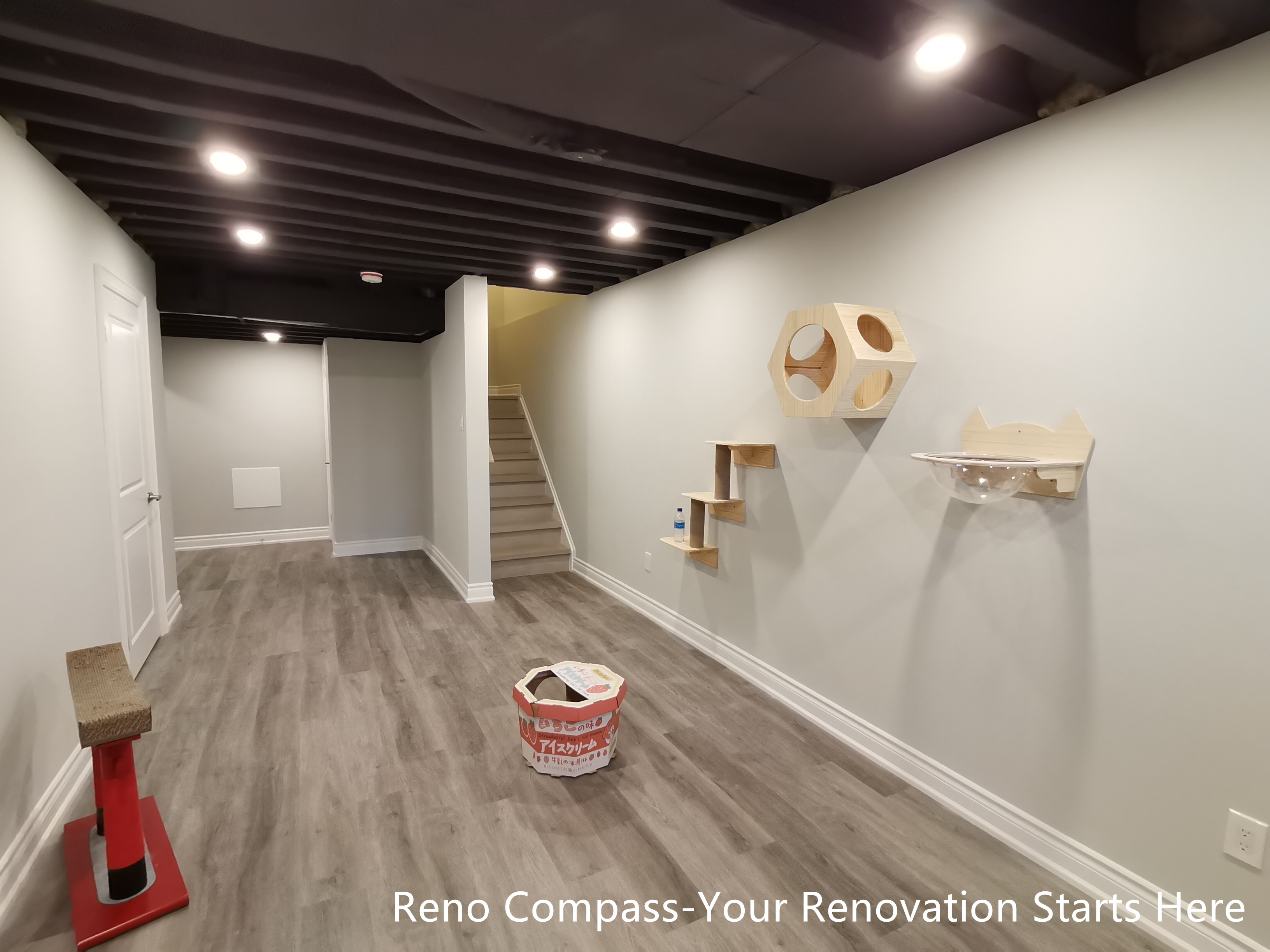 This Vaughan basement renovation features an industrial-style design with a sprayed black open ceiling, recessed lighting, and durable flooring that enhances both function and visual depth. The space is thoughtfully customized with wall-mounted cat climbing structures, creating a pet-friendly environment without compromising the clean, modern aesthetic. With clear circulation and a flexible layout, the basement feels open and comfortable despite its compact footprint. Designed and completed by Reno Compass, this renovation demonstrates a balanced approach to industrial design, space efficiency, and everyday usability.