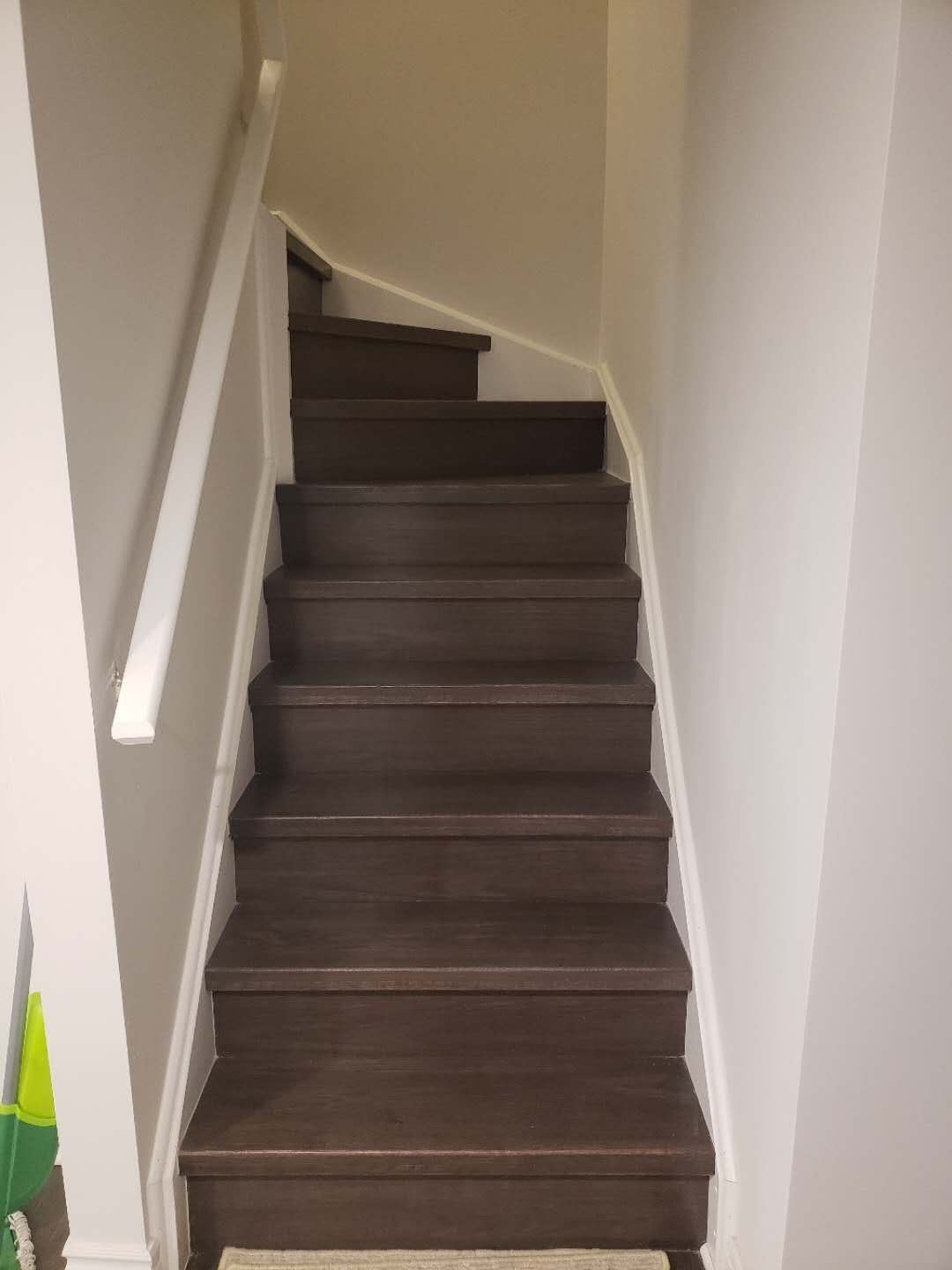 This Markham basement renovation includes a staircase upgrade featuring durable dark wood steps and clean white railings for a modern, streamlined look. The refreshed stair design enhances safety and visual continuity between the main floor and the finished basement. Neutral wall tones and updated trim create a bright, cohesive transition space while maximizing durability for daily use. This professionally completed staircase renovation reflects quality craftsmanship and thoughtful design, adding both function and aesthetic value to the overall Markham basement renovation project.