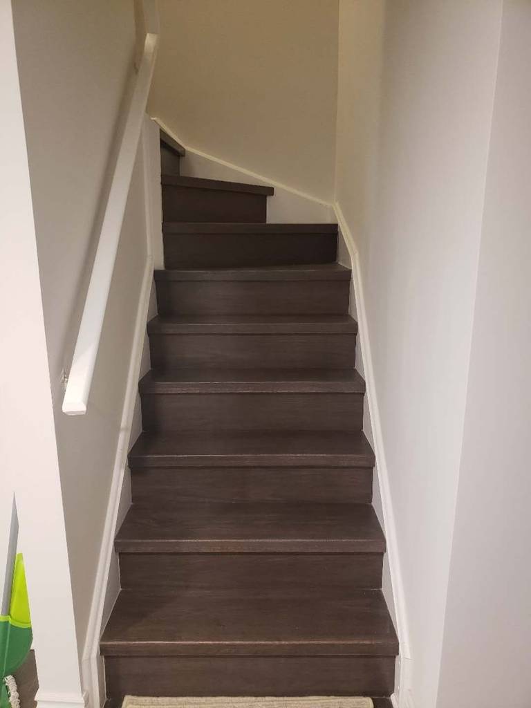 This Markham basement renovation includes a staircase upgrade featuring durable dark wood steps and clean white railings for a modern, streamlined look. The refreshed stair design enhances safety and visual continuity between the main floor and the finished basement. Neutral wall tones and updated trim create a bright, cohesive transition space while maximizing durability for daily use. This professionally completed staircase renovation reflects quality craftsmanship and thoughtful design, adding both function and aesthetic value to the overall Markham basement renovation project.