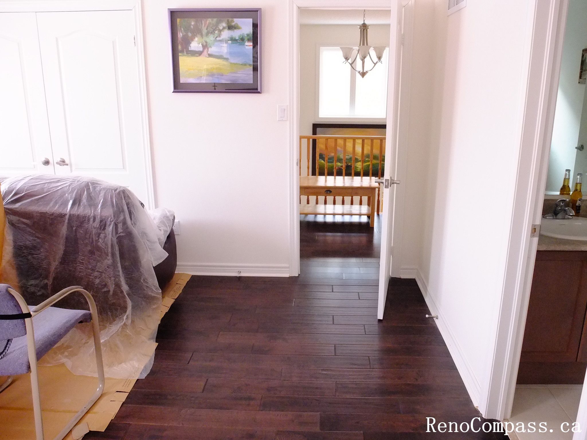 Toronto home hardwood flooring installation featuring deep-toned wood floors throughout the hallway and upper level. This professional flooring renovation enhances brightness, durability, and visual continuity, completed by Reno Compass for a clean and modern interior upgrade.