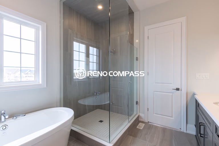Contemporary bathroom renovation in Newmarket featuring a frameless glass shower enclosure, freestanding bathtub, and modern tile flooring. This elegant layout was completed by a professional Toronto renovation company, creating a bright, spacious and comfortable bathroom environment.