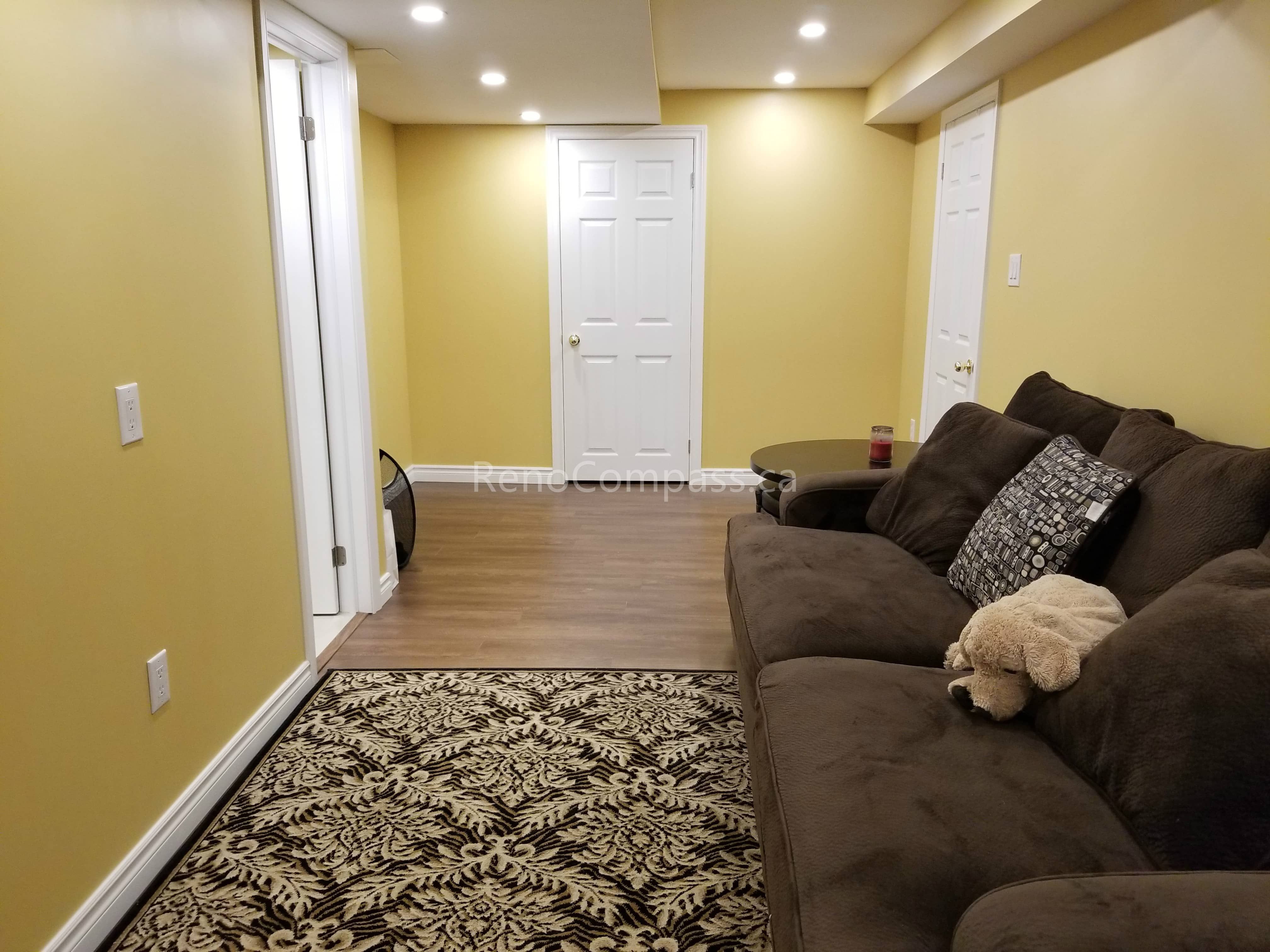 This Vaughan basement renovation features a bright and comfortable finished living area with newly installed wood-look vinyl flooring, recessed pot lights, and a clean modern layout. The refreshed space offers a warm and functional environment ideal for family use, entertainment, or a secondary living room. Completed by Reno Compass Inc., this basement upgrade improves lighting, durability, and overall home comfort while adding practical living space.