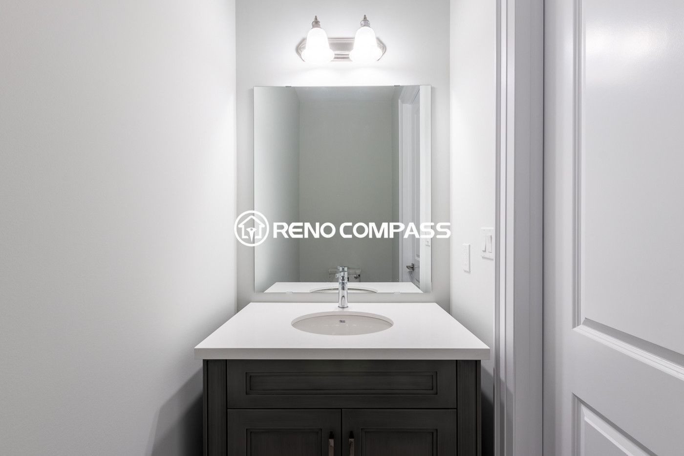 Simple and elegant powder room renovation in Newmarket featuring a modern vanity cabinet, quartz countertop, wall mirror and contemporary lighting fixture. Completed by a professional Toronto renovation company, this compact bathroom design maximizes space while maintaining a clean and stylish look.