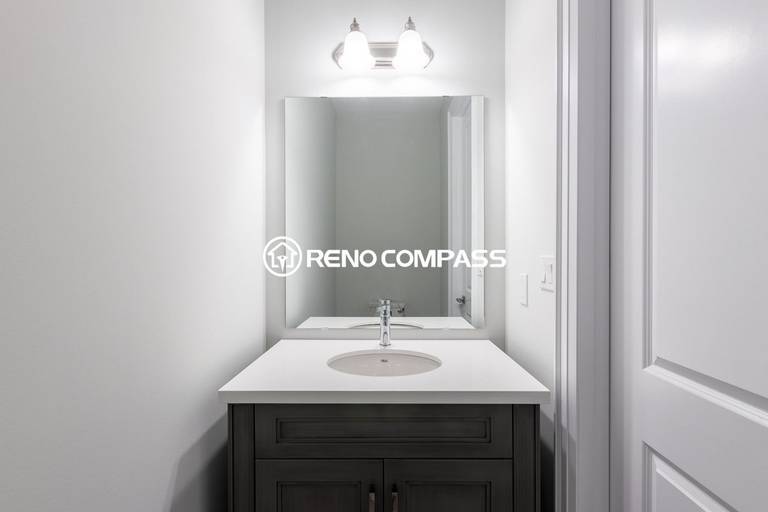 Simple and elegant powder room renovation in Newmarket featuring a modern vanity cabinet, quartz countertop, wall mirror and contemporary lighting fixture. Completed by a professional Toronto renovation company, this compact bathroom design maximizes space while maintaining a clean and stylish look.
