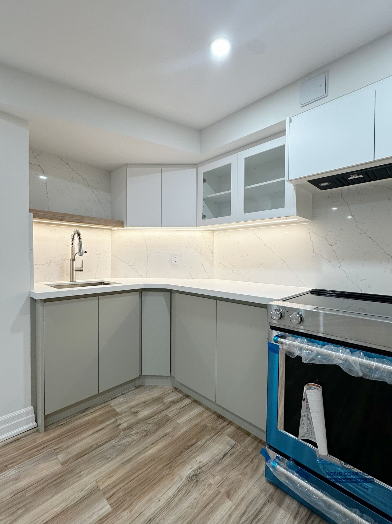 This image focuses on a detailed view of the basement kitchen renovation in Pickering, highlighting the corner layout and functional workspace design. Custom cabinetry, integrated under-cabinet lighting, and a continuous countertop create a practical and efficient kitchen setup suitable for everyday use. The corner sink placement improves workflow while maintaining a clean and organized appearance. Neutral finishes and consistent flooring allow the kitchen area to blend seamlessly into the surrounding basement living space, supporting a cohesive and flexible lower-level layout.
Location: Pickering · Toronto Contractor: Reno Compass