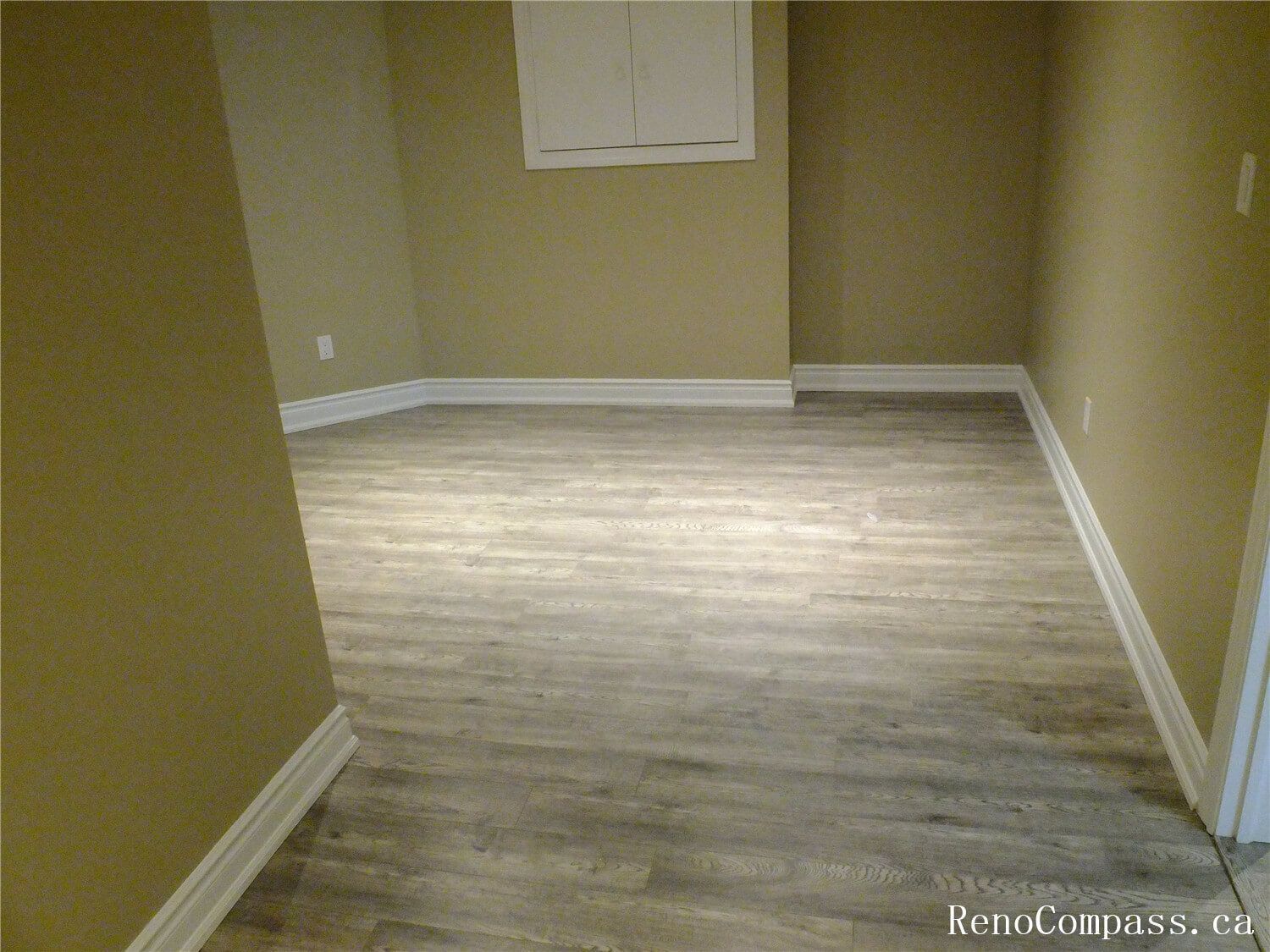 A bright, expansive basement transformation in Ajax, Ontario. This open-concept living space features energy-efficient recessed pot lighting, modern grey vinyl plank flooring, and a neutral color palette. Expertly designed for a home theater, family play area, or exercise room.