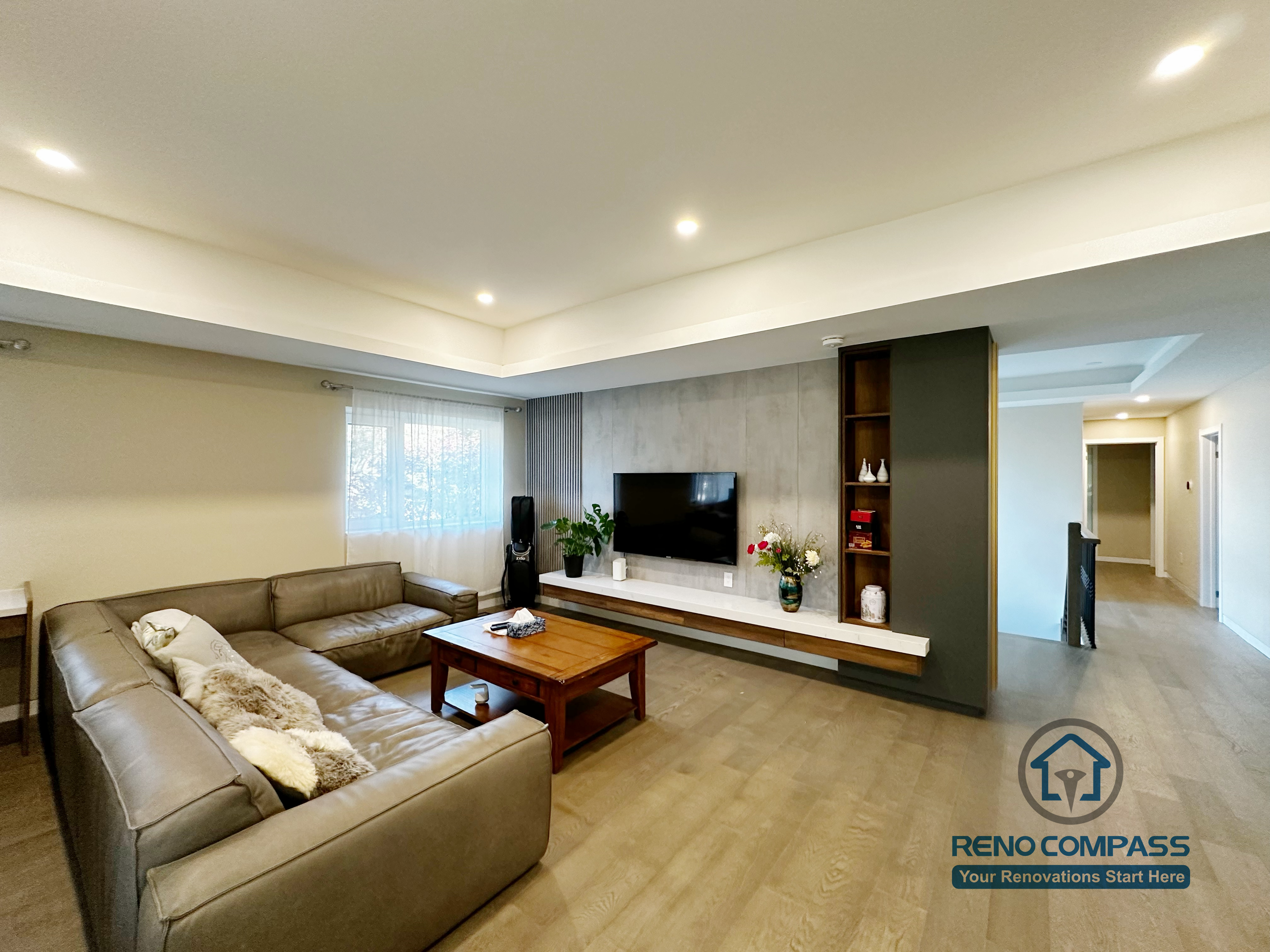 Modern living room completed as part of a North York interior renovation. This space features an open layout, recessed ceiling lighting, wide-plank flooring, and a custom TV feature wall with integrated shelving. Designed to balance comfort, storage, and visual order by a professional Toronto renovation company.