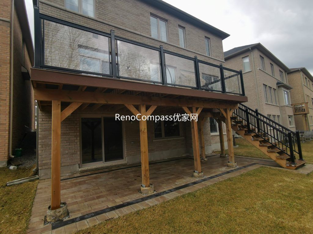 Custom elevated deck renovation in Aurora featuring composite decking, modern glass and aluminum railings, and a covered patio structure below. This professionally built outdoor space provides added functionality, weather protection, and a stylish backyard upgrade that enhances both usability and property value.