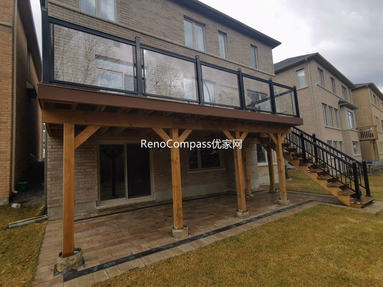 Custom elevated deck renovation in Aurora featuring composite decking, modern glass and aluminum railings, and a covered patio structure below. This professionally built outdoor space provides added functionality, weather protection, and a stylish backyard upgrade that enhances both usability and property value.