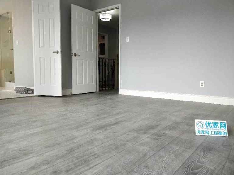 This renovated room in Ajax features modern grey wood flooring, fresh wall finishes, and enhanced natural lighting from the window. The clean and minimalist design creates a bright and comfortable living space, ideal for bedrooms or flexible use areas. As part of a full house renovation, the flooring upgrade improves durability while elevating the overall interior style.