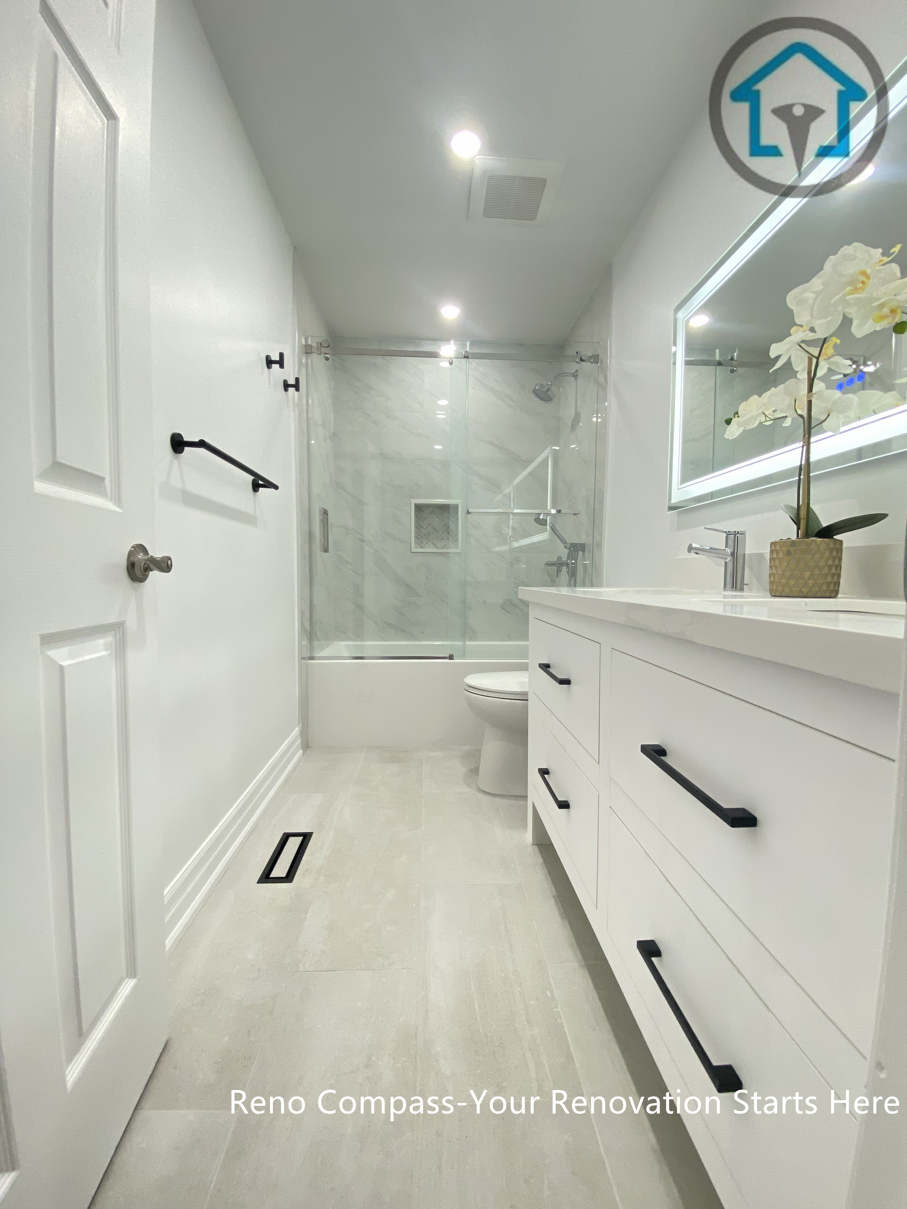 This Pickering bathroom renovation highlights a streamlined layout designed to maximize visual length and openness. A custom vanity with matte black hardware runs along one side, paired with light-toned flooring to enhance brightness. The frameless glass shower enclosure and marble-style wall tiles create a seamless transition, giving the bathroom a clean, modern, and well-balanced feel.
