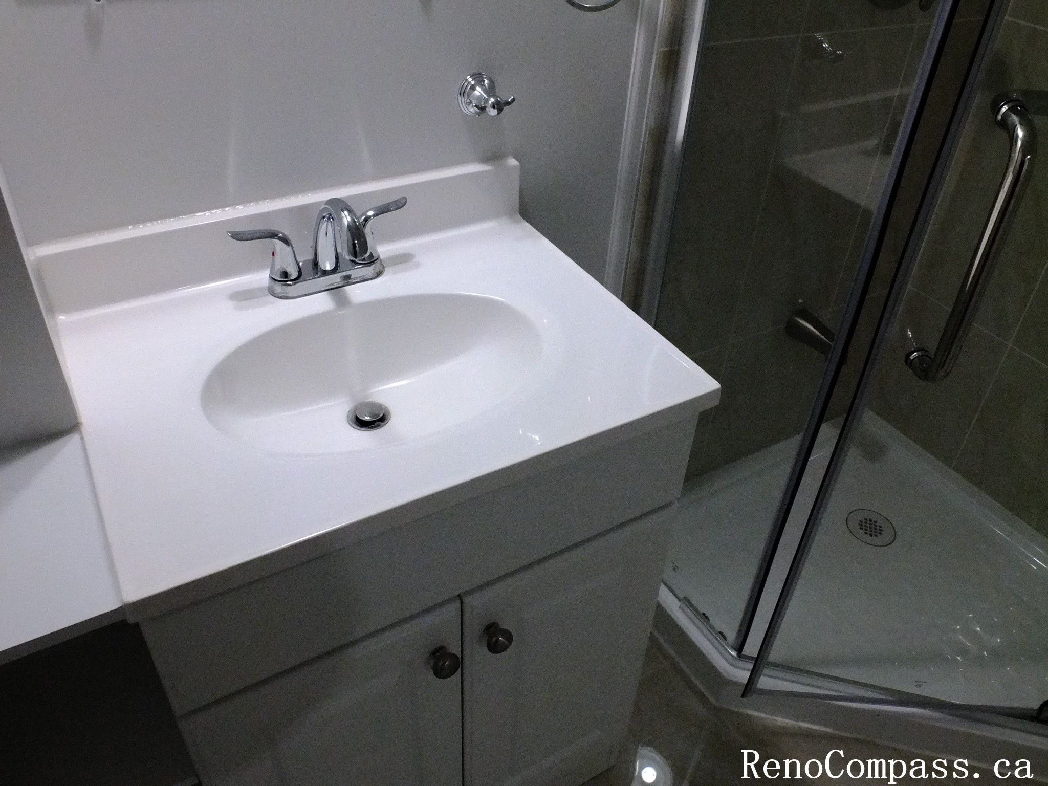 Minimalist white vanity with modern sink and faucet installed during a Richmond Hill basement bathroom renovation, blending style and practicality by Reno Compass