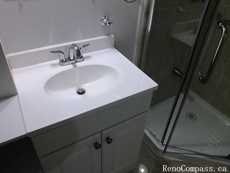Minimalist white vanity with modern sink and faucet installed during a Richmond Hill basement bathroom renovation, blending style and practicality by Reno Compass