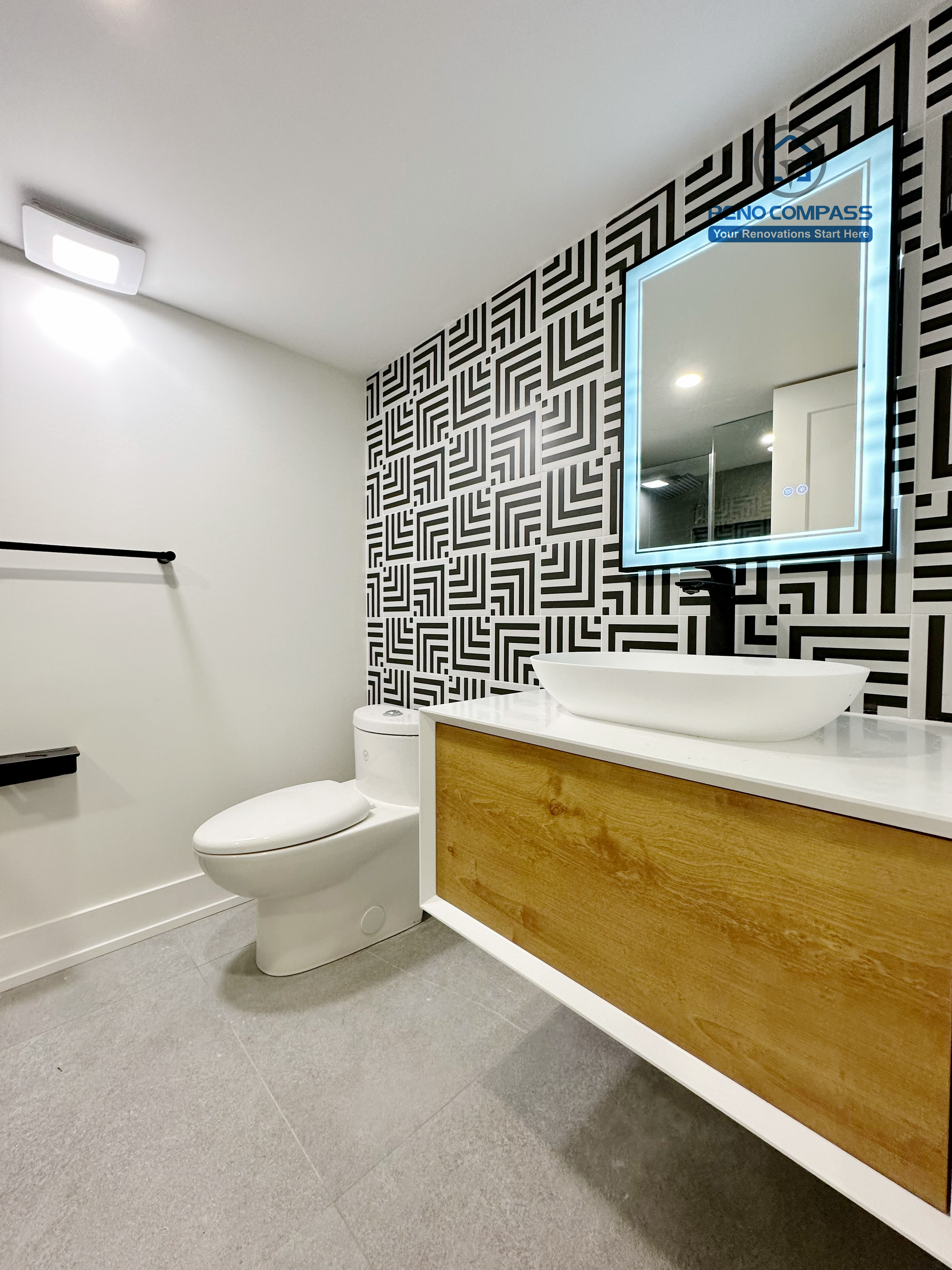 Stylish bathroom renovation in Richmond Hill highlighting a bold geometric feature wall, floating wood vanity, vessel sink, and illuminated mirror, creating a modern and visually striking bathroom space.