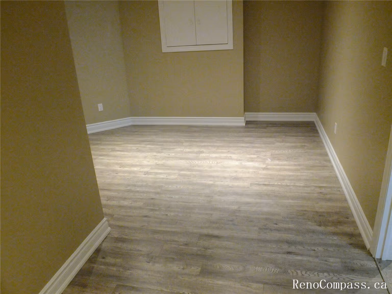 View of a finished basement room in this Ajax basement renovation, featuring durable vinyl plank flooring, neutral wall tones, and recessed pot lights for bright, even lighting. The clean layout and modern finishes make this space ideal for a home office, guest room, or recreation area. Completed by a professional Toronto Renovation Company, the renovation focuses on comfort, functionality, and long-lasting materials suitable for basement living spaces.
