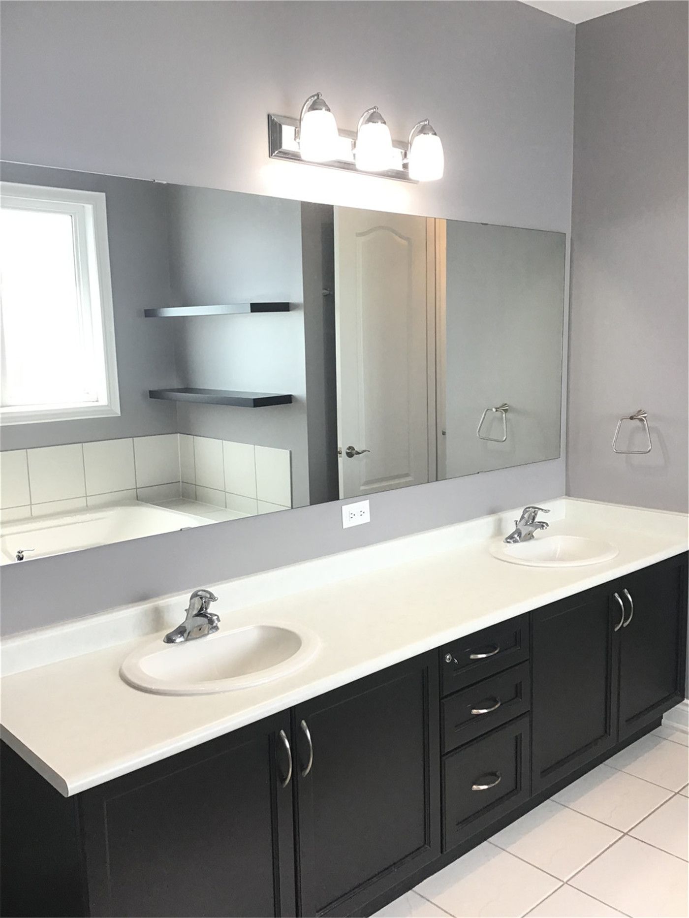 This Markham full home renovation features a spacious bathroom with a double vanity, large wall mirror, and modern lighting fixtures. The design provides ample storage and functionality for daily use, while the clean layout and neutral tones create a bright and organized space. Completed by a trusted Toronto Renovation Company, this bathroom combines practicality with contemporary design.