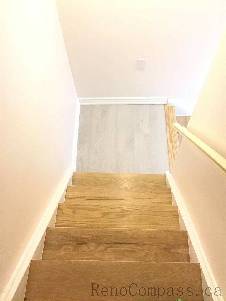 Newly installed modern wooden staircase for this Pickering basement renovation project, featuring natural-tone wood steps, clean white side walls, and a bright contemporary finish. The upgraded basement stairs improve both safety and visual flow, creating a seamless transition to the newly finished lower level. Completed by Reno Compass Inc., a professional Toronto Renovation Company.