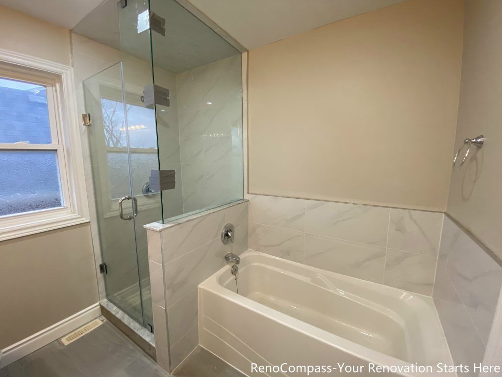 This Mississauga interior renovation features a practical bathroom layout combining a bathtub with a frameless glass shower enclosure. The marble-look wall tiles provide a clean and durable finish around the tub, while the glass shower improves brightness and spatial openness. Natural light from the window enhances the overall comfort of the space, making this tub and shower combination ideal for family use and long-term daily functionality.