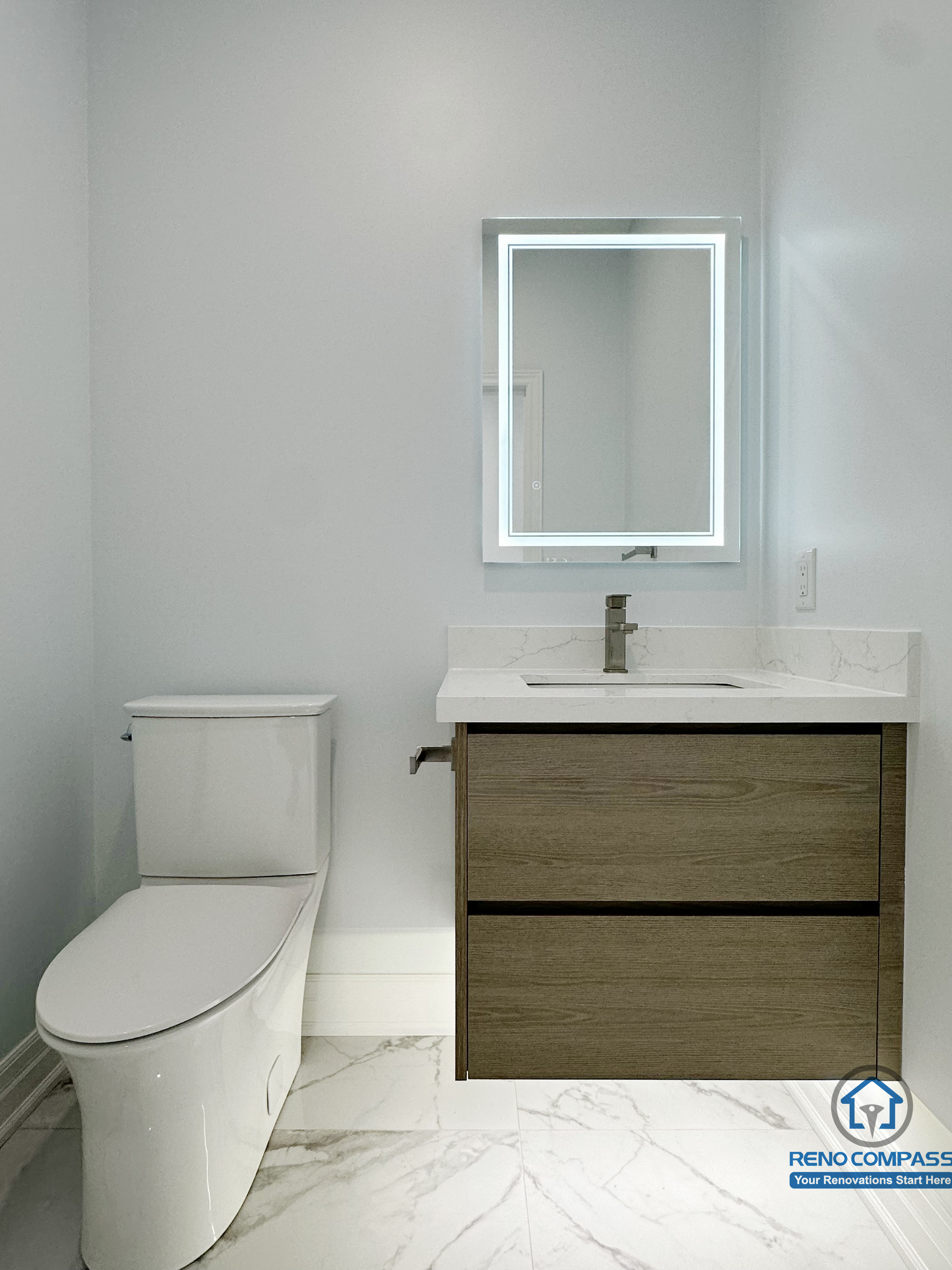 Minimalist bathroom vanity featuring a floating wood-finish cabinet, integrated LED mirror, and marble-look flooring, creating a clean, modern, and space-efficient powder room design.