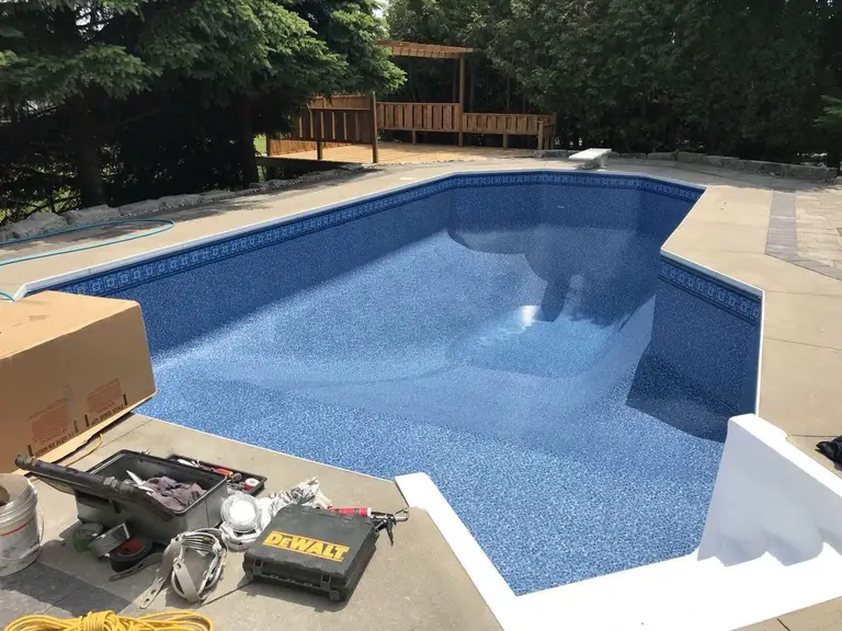 After renovation photo of a fully restored backyard swimming pool in Toronto. The new bright blue liner, clean water, and resurfaced edges highlight the professional pool transformation from old and damaged to modern and inviting. Expert pool renovation by local Toronto specialists.