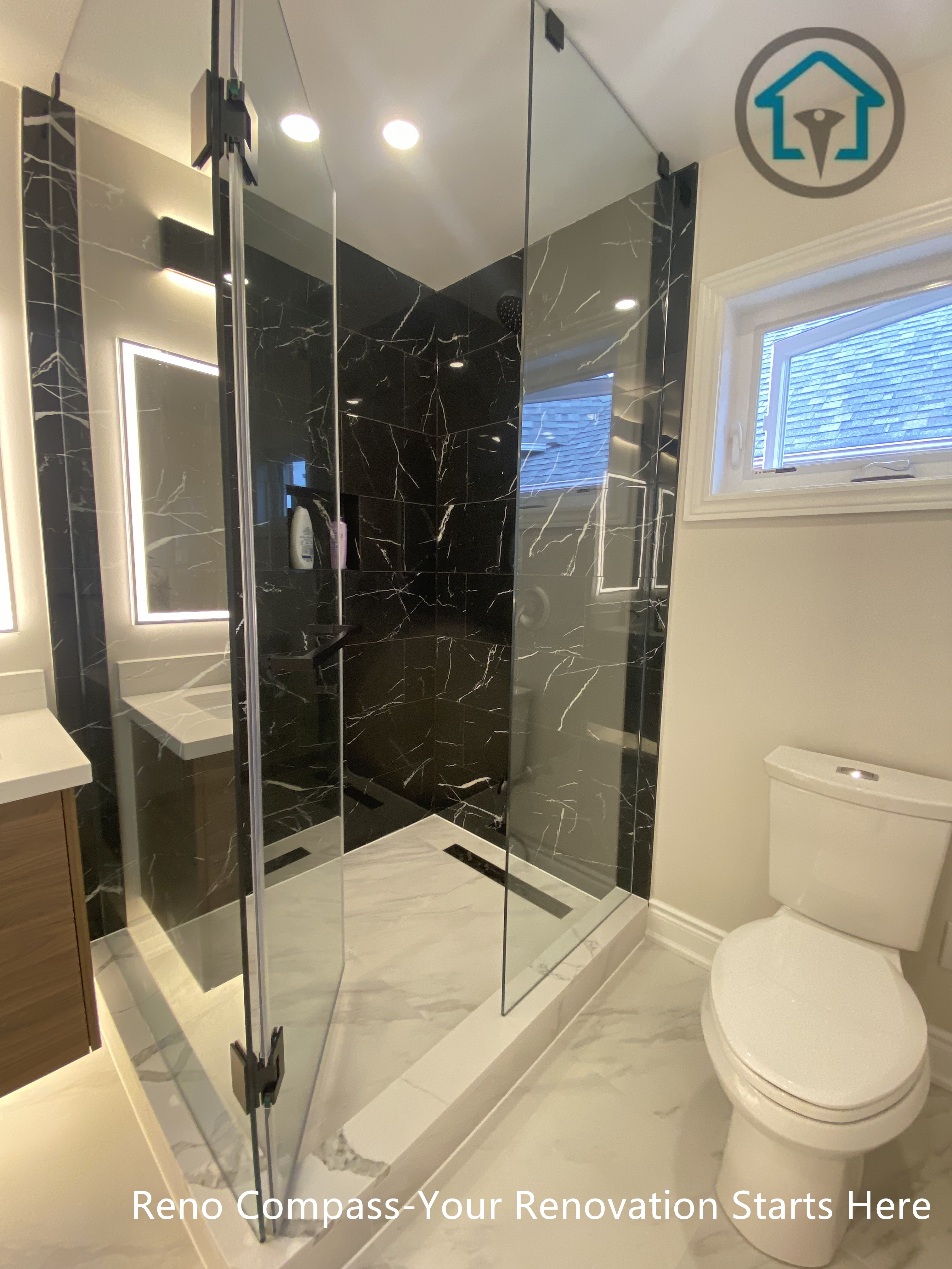 This Richmond Hill bathroom renovation features a modern frameless glass walk-in shower with elegant black marble wall tiles and sleek chrome fixtures. The upgraded layout improves space efficiency after converting one bathroom into two, adding functionality and value to the home. Bright LED mirror lighting, marble-style flooring, and a clean contemporary design create a luxurious and practical bathroom completed by a trusted Toronto renovation company.