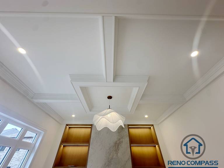 Coffered ceiling (waffle ceiling) design in a Toronto new home upgrade, featuring structured panel detailing, integrated lighting, and a modern fireplace feature wall.