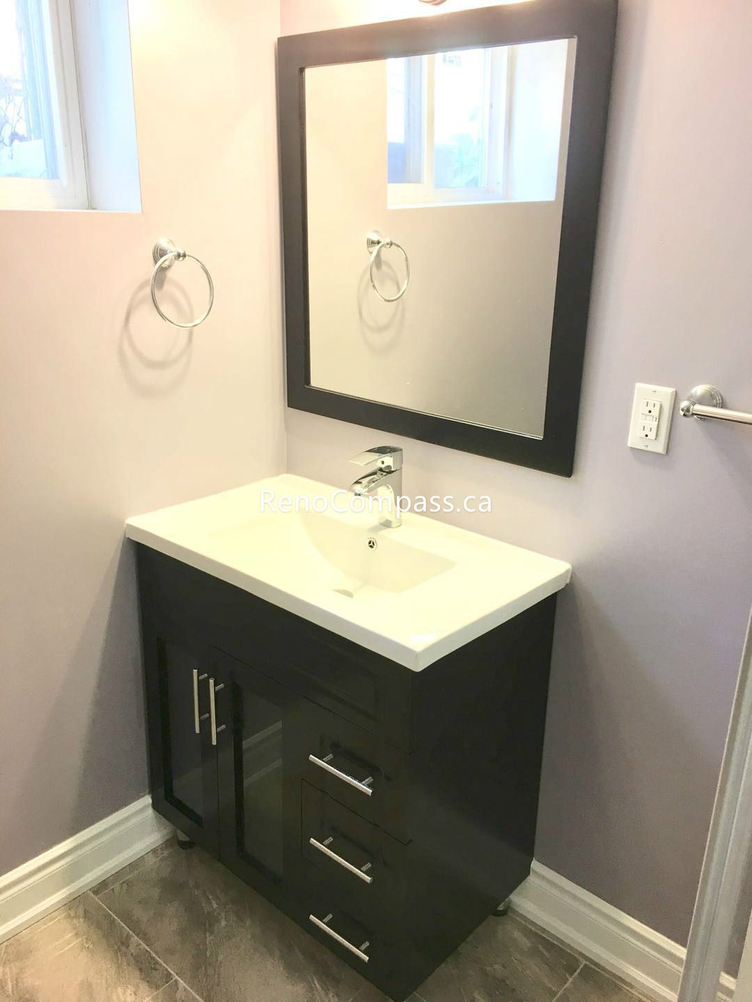 This Toronto basement renovation features a modern bathroom vanity with quartz countertop, under-mount sink, and sleek black cabinet design. The large framed mirror and neutral wall tones create a bright and elegant space, while durable tile flooring ensures long-term performance. Completed by a trusted Toronto renovation company, this basement bathroom upgrade enhances functionality, storage, and contemporary home value.