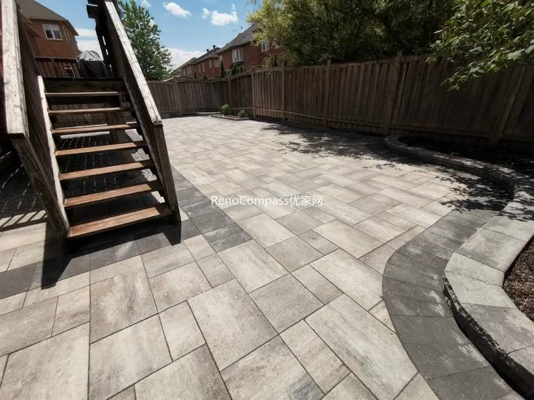 Backyard interlocking patio project in Richmond Hill designed around a wooden deck. Featuring clean, neutral-toned stones arranged for durability and aesthetic appeal — a perfect balance of function and style by Reno Compass.
