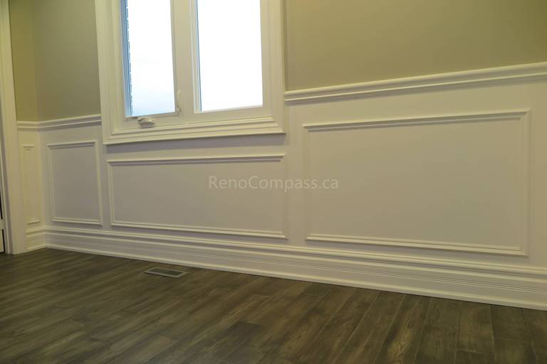 This Markham interior renovation showcases a bright and elegant living space featuring custom wall panel molding, crown molding details, and newly installed dark hardwood flooring. Recessed LED pot lights provide balanced lighting throughout the room, while large windows enhance natural light and openness. Completed by Reno Compass, a professional renovation contractor specializing in high-quality interior renovations and custom finishing services across Markham and the Greater Toronto Area.