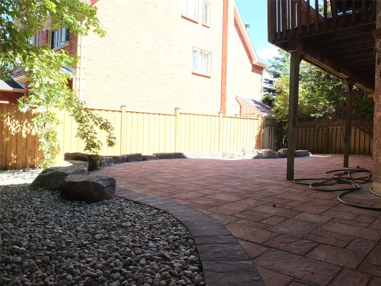 This Aurora landscaping renovation highlights a curved interlocking patio seamlessly integrated with a decorative gravel relaxation area. The contrasting stone border defines the transition between the paver surface and the natural stone feature zone, creating visual depth and balance.

Reno Compass Inc. carefully designed the layout to preserve mature trees while enhancing usability. The addition of river stone, large accent rocks, and a hammock-ready space transforms the backyard into a tranquil retreat that blends structure with nature.