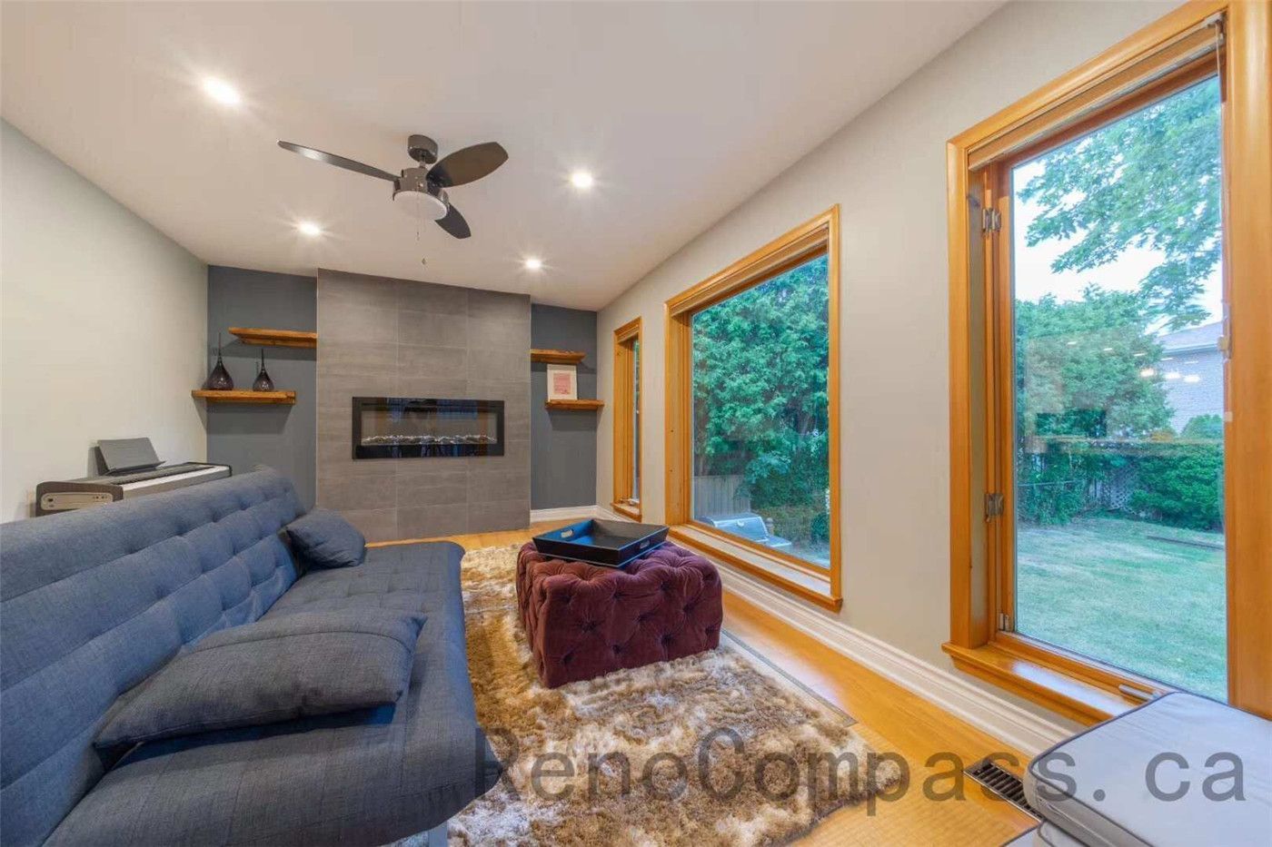 This North York interior renovation features a stylish living room upgrade with a sleek modern fireplace, custom floating shelves, and large windows that bring in abundant natural light. The space combines warm wood window frames, recessed lighting, and contemporary furnishings to create a cozy yet sophisticated atmosphere. Completed by a professional Toronto renovation company, the project enhances both comfort and aesthetics, delivering a bright and inviting family living space.