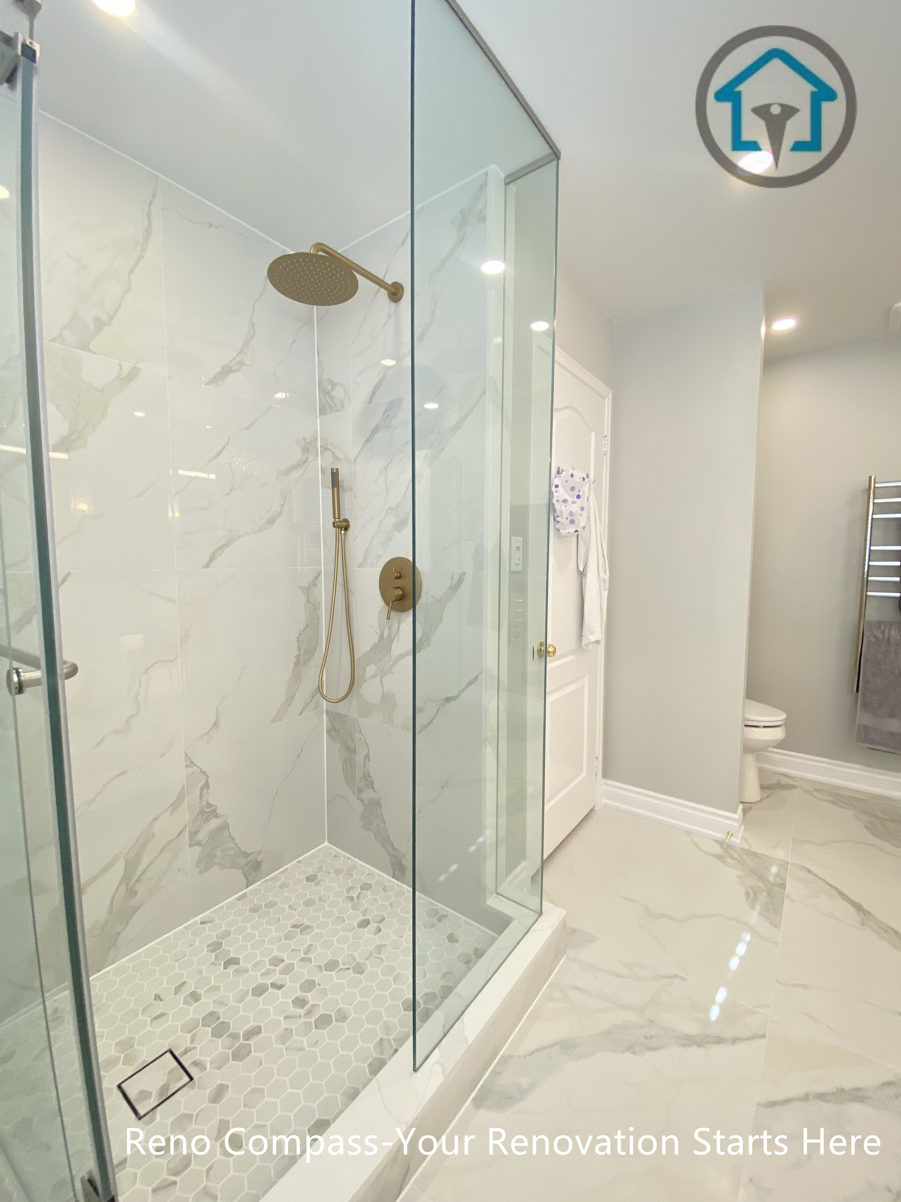 This Mississauga bathroom renovation features a spacious walk-in shower enclosed with frameless clear glass panels to enhance openness and natural light. Large-format marble-look wall tiles are paired with a mosaic tile shower floor for slip resistance and visual contrast. Gold-tone shower fixtures add warmth and elegance, while a built-in wall niche provides functional storage without disrupting the clean layout. The shower design prioritizes comfort, drainage efficiency, and long-term durability through precise detailing and quality materials.