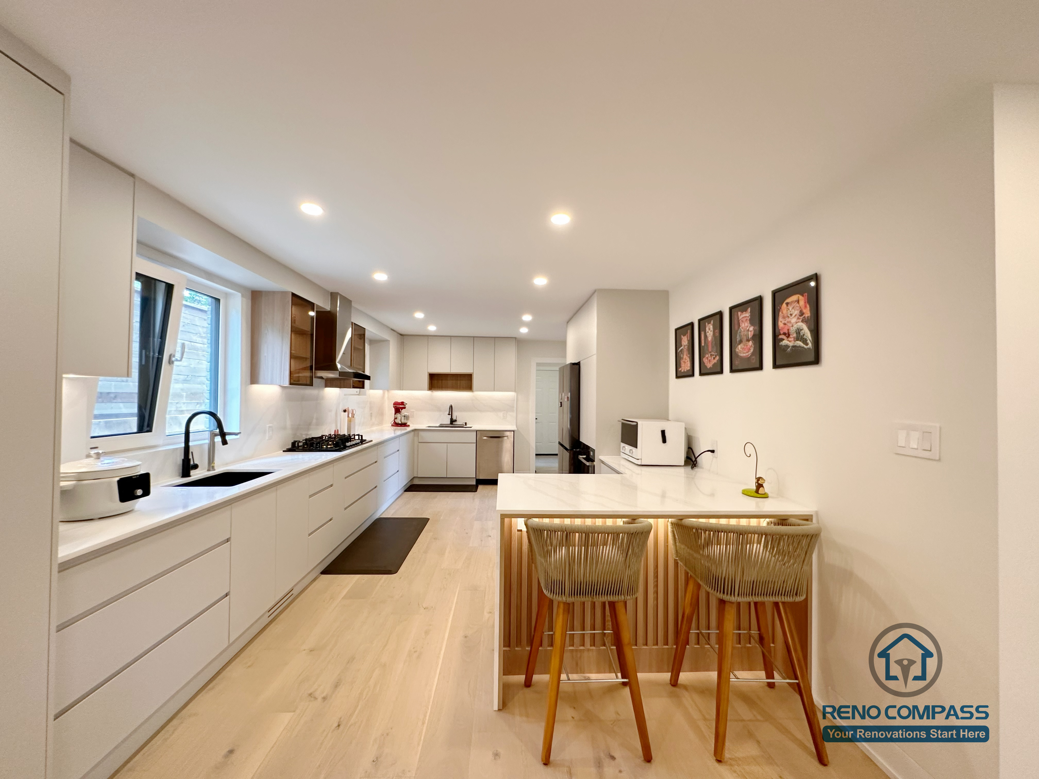 A modern open-concept kitchen renovation in Toronto featuring custom cabinetry, a functional kitchen island with seating, and clean-lined built-in storage. The long galley layout enhances workflow and space efficiency, showcasing refined craftsmanship by a professional Toronto renovation company.