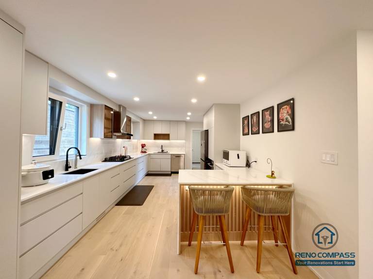 A modern open-concept kitchen renovation in Toronto featuring custom cabinetry, a functional kitchen island with seating, and clean-lined built-in storage. The long galley layout enhances workflow and space efficiency, showcasing refined craftsmanship by a professional Toronto renovation company.