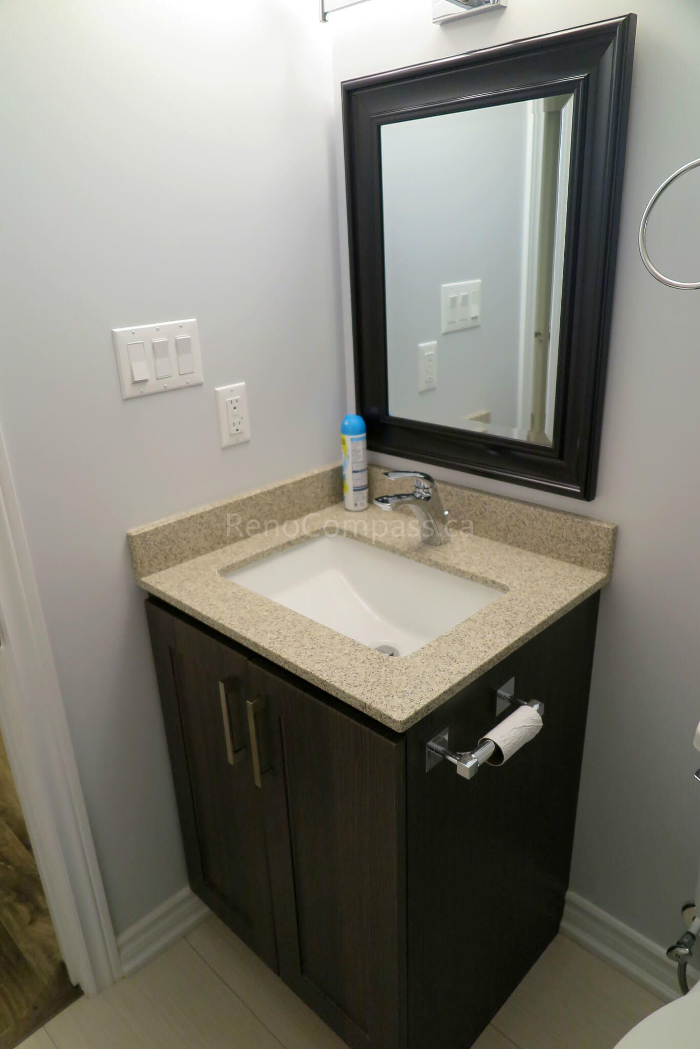 After photo from a Richmond Hill basement renovation featuring a sleek bathroom vanity with a granite countertop, under-mount sink, and dark wood cabinetry. A modern and space-efficient design perfect for basement bathrooms.