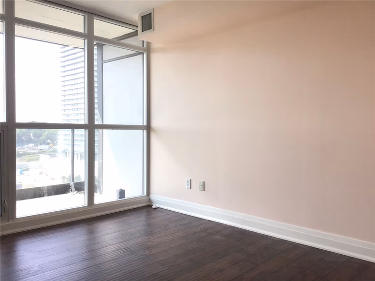 This North York condo renovation features a bright living area with floor-to-ceiling windows, dark wood flooring, and a clean, open layout. Abundant natural light and city views enhance the sense of space, making the room ideal for modern condo living, relaxation, or flexible daily use.