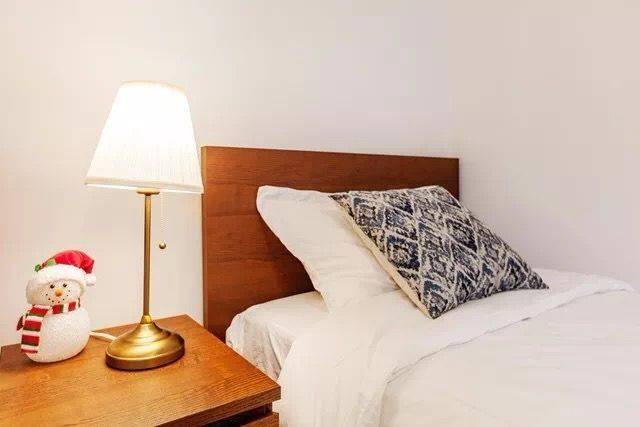 This Toronto interior renovation showcases a bright and comfortable bedroom featuring clean white walls, soft natural lighting, and simple modern furnishings. The space includes elegant curtains, a cozy bed, and minimal décor that creates a peaceful and relaxing atmosphere. The renovation enhances comfort and functionality, offering a fresh and welcoming bedroom environment in a modern Toronto home.