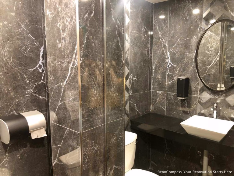This Barrie commercial renovation features a modern washroom design with full marble-style wall tiles, glass shower enclosure, and sleek black countertop vanity. The space combines durability with a high-end aesthetic to enhance customer experience in a commercial setting. Completed by Reno Compass Inc., a professional Toronto renovation company, this project highlights quality workmanship for restaurants, cafés, and retail commercial interiors across Barrie and the GTA.