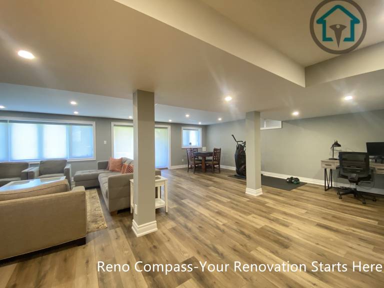 An open-concept basement living area completed as part of a Vaughan basement renovation. This finished basement features recessed ceiling lighting, integrated structural columns, durable wood-look flooring, and a spacious layout designed for family gatherings, entertainment, and everyday relaxation.