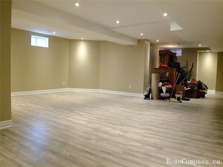 This Ajax basement renovation features a spacious open-concept layout with newly installed modern vinyl flooring, smooth painted walls, and recessed pot lights that brighten the entire space. The neutral color palette and clean finishes create a comfortable and versatile living area suitable for a family room, entertainment space, or home office. Completed by a professional Toronto Renovation Company, this project focuses on durability, efficient lighting design, and practical basement living upgrades for modern homes.